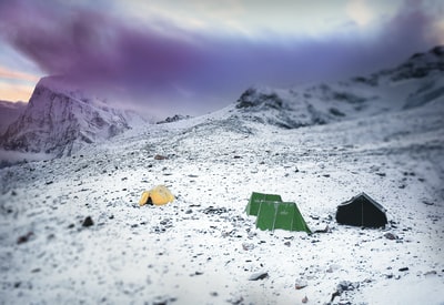 冰冷表面中间的绿色和黄色露营帐篷